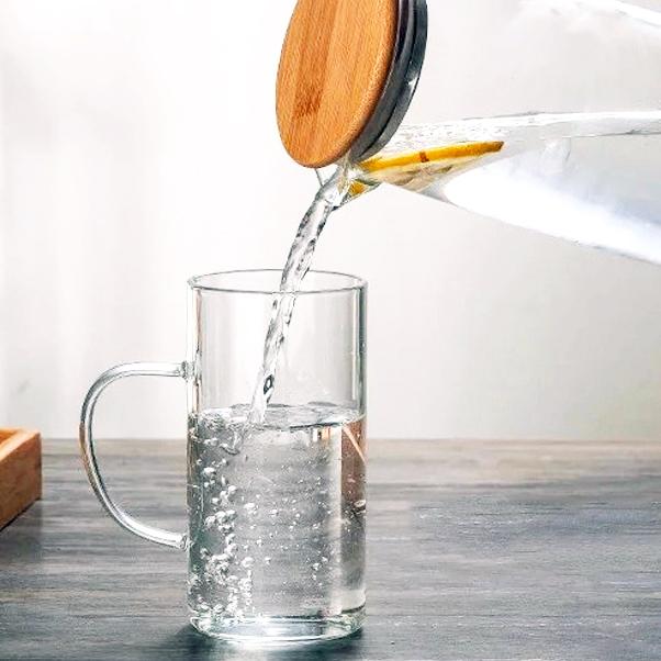 Hand-blown glass and bamboo pitcher with matching cups set by Tea + Linen, featuring clear glass and natural bamboo accents.