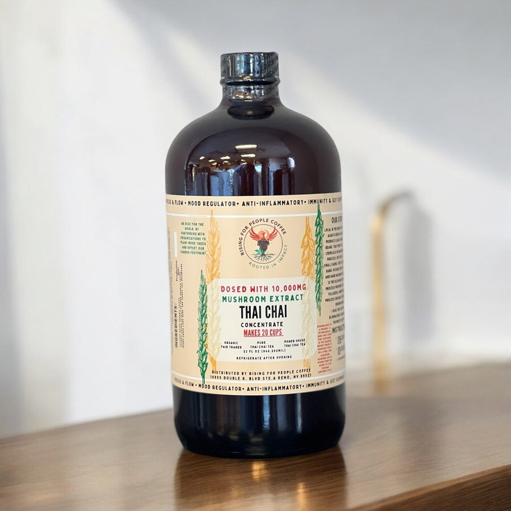 Bottle of Happy Mushroom Thai Chai Tea Concentrate by Rising For People Coffee Co. with a label featuring vibrant colors and mushroom graphics.