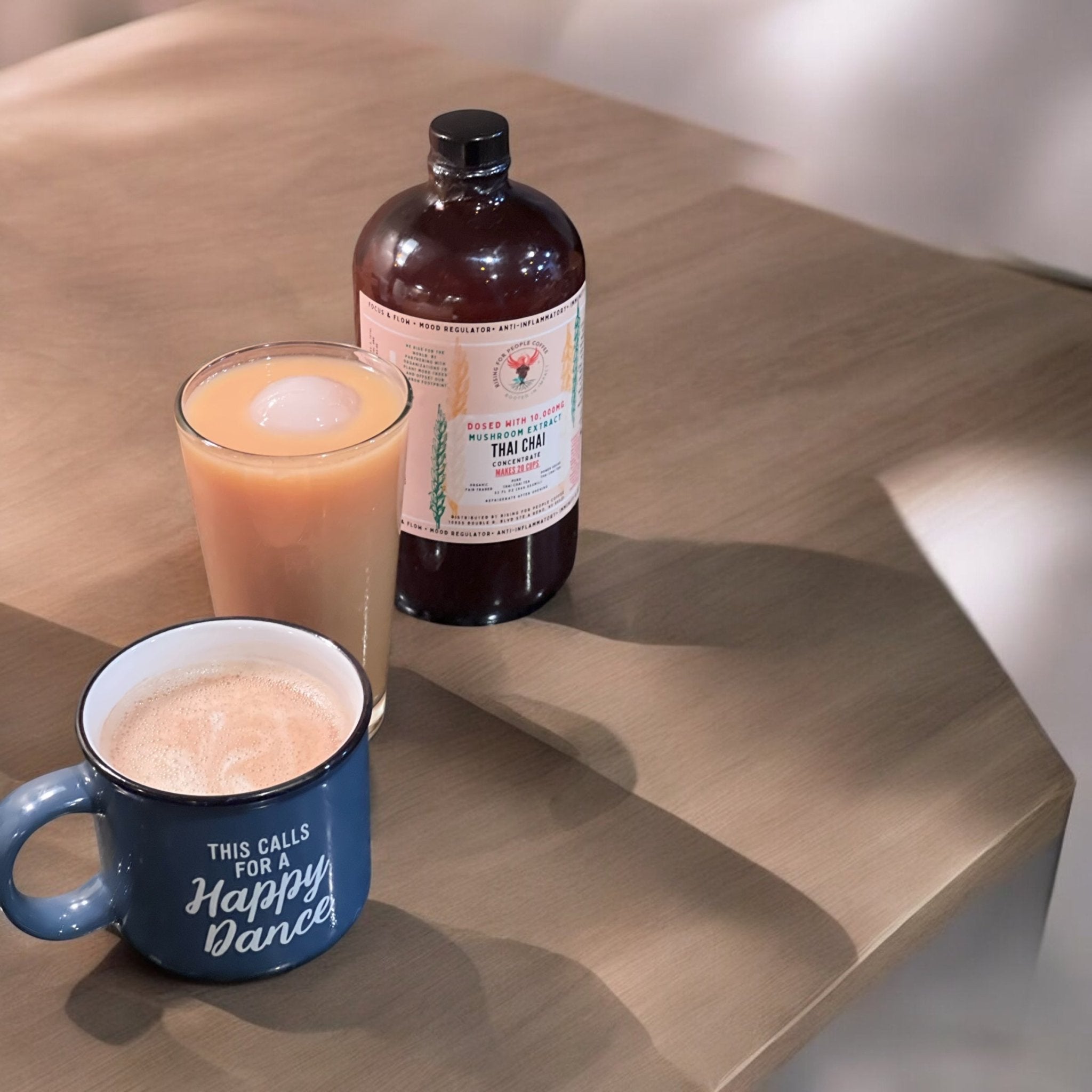 Bottle of Rising For People Thai Chai Tea Concentrate with a happy mushroom label, showcasing the tea concentrate in a clear bottle.