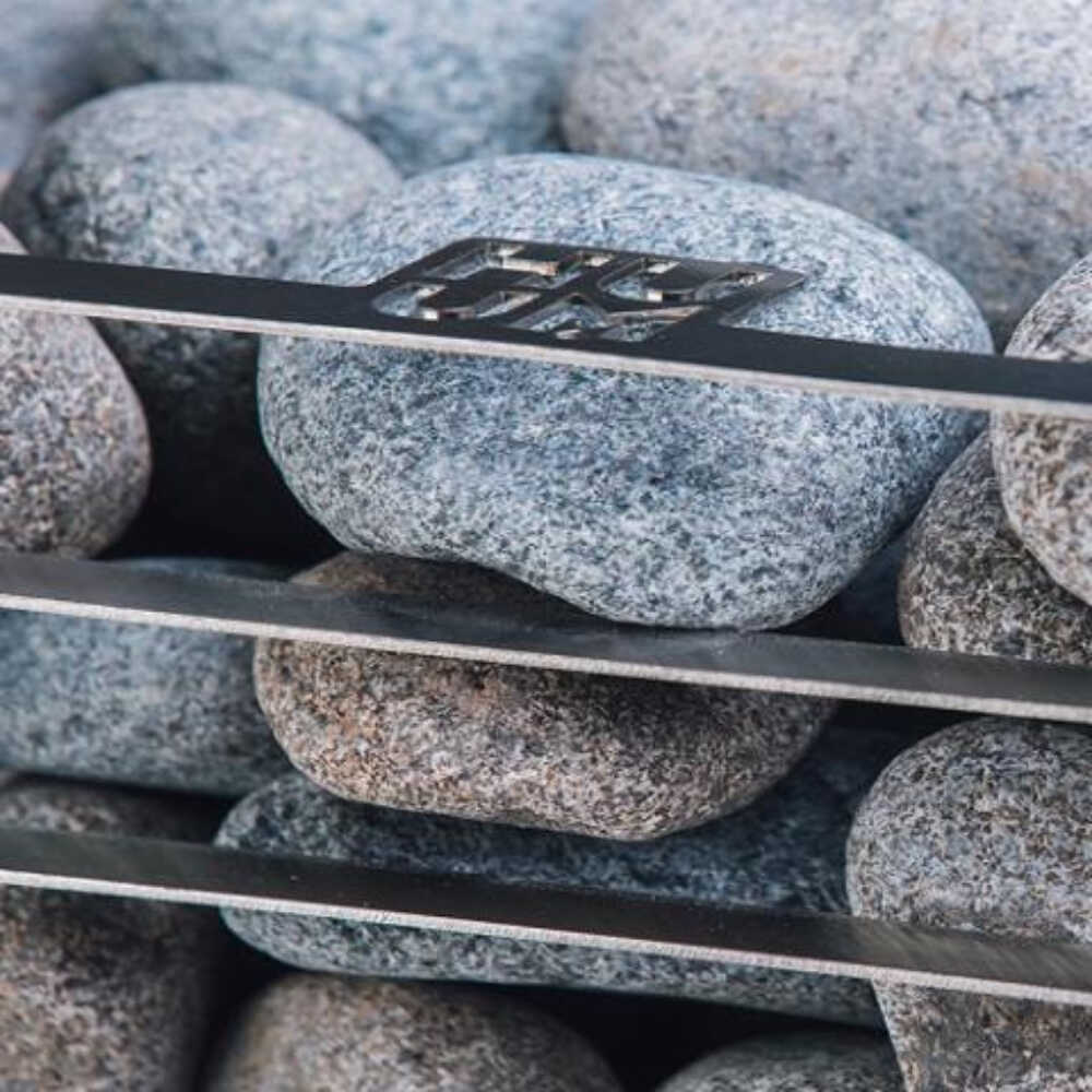Huum Cliff Mini 4 3.5KW electric sauna heater with digital controller and sauna stones, in use with visible stones.