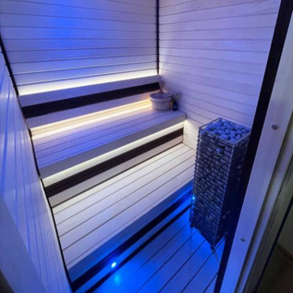 Huum Cliff Slim electric stainless steel sauna heater with digital controller and sauna stones inside a sauna room.