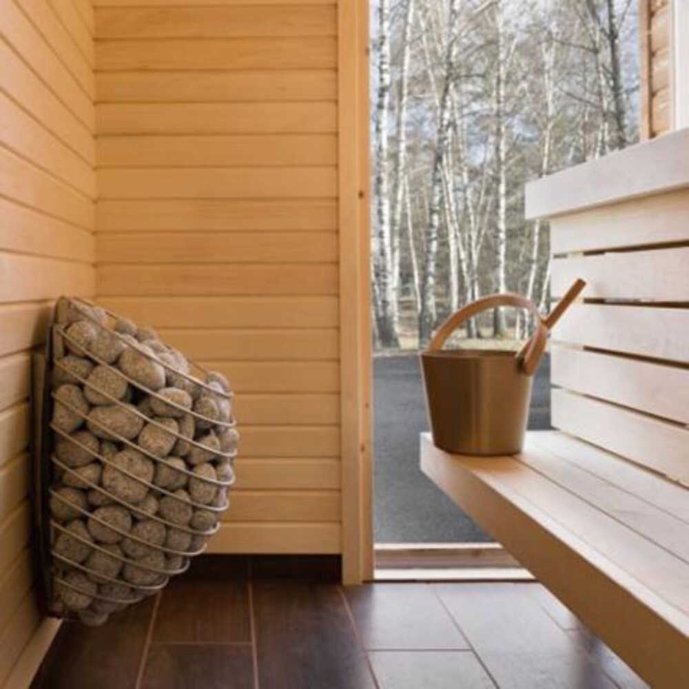 Wall-mounted Huum Drop 240V sauna heater with digital controller and sauna stones, featuring a water-drop design, right view.