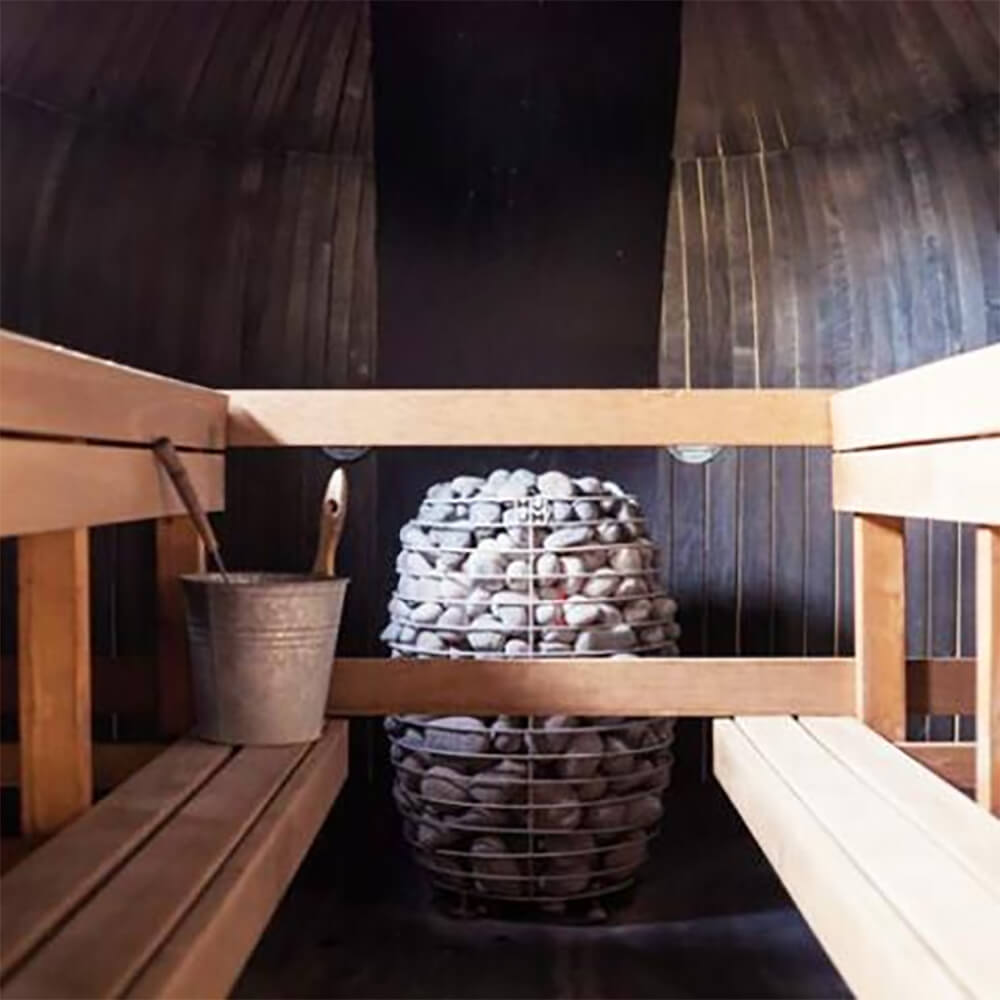 Huum Hive Premium 18kW floor-mounted sauna heater with UKU control, sauna stones, and extension box inside a sauna room.