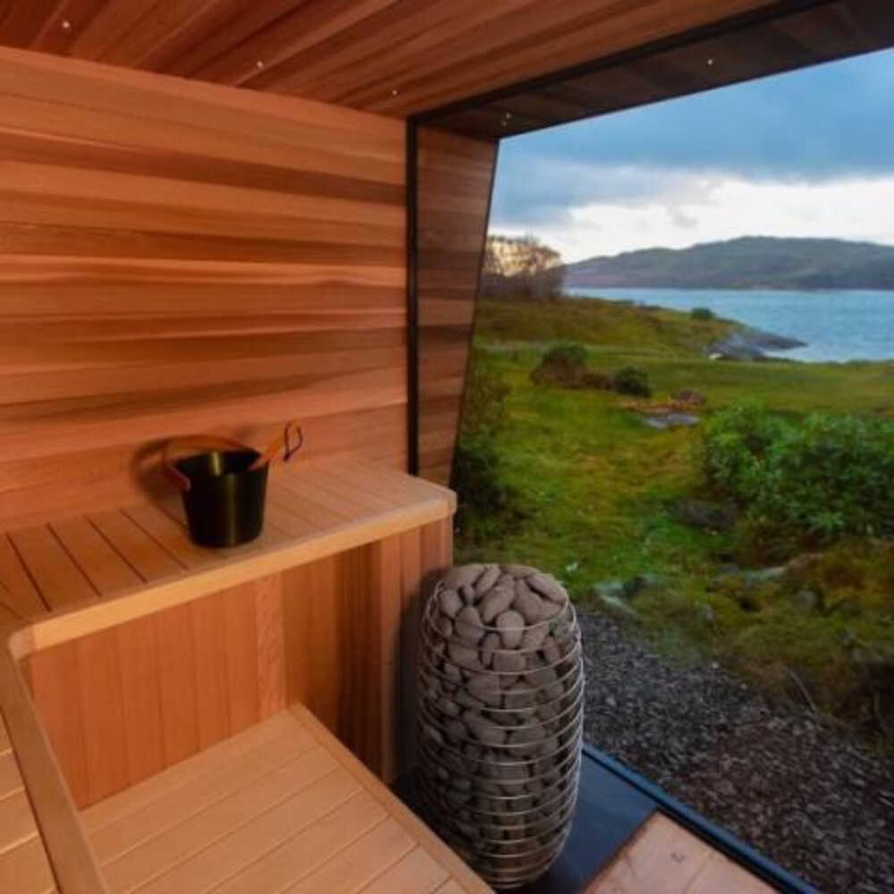 Huum Hive Mini Floor Mount Steel Sauna Heater with digital controller and sauna stones inside a sauna room.