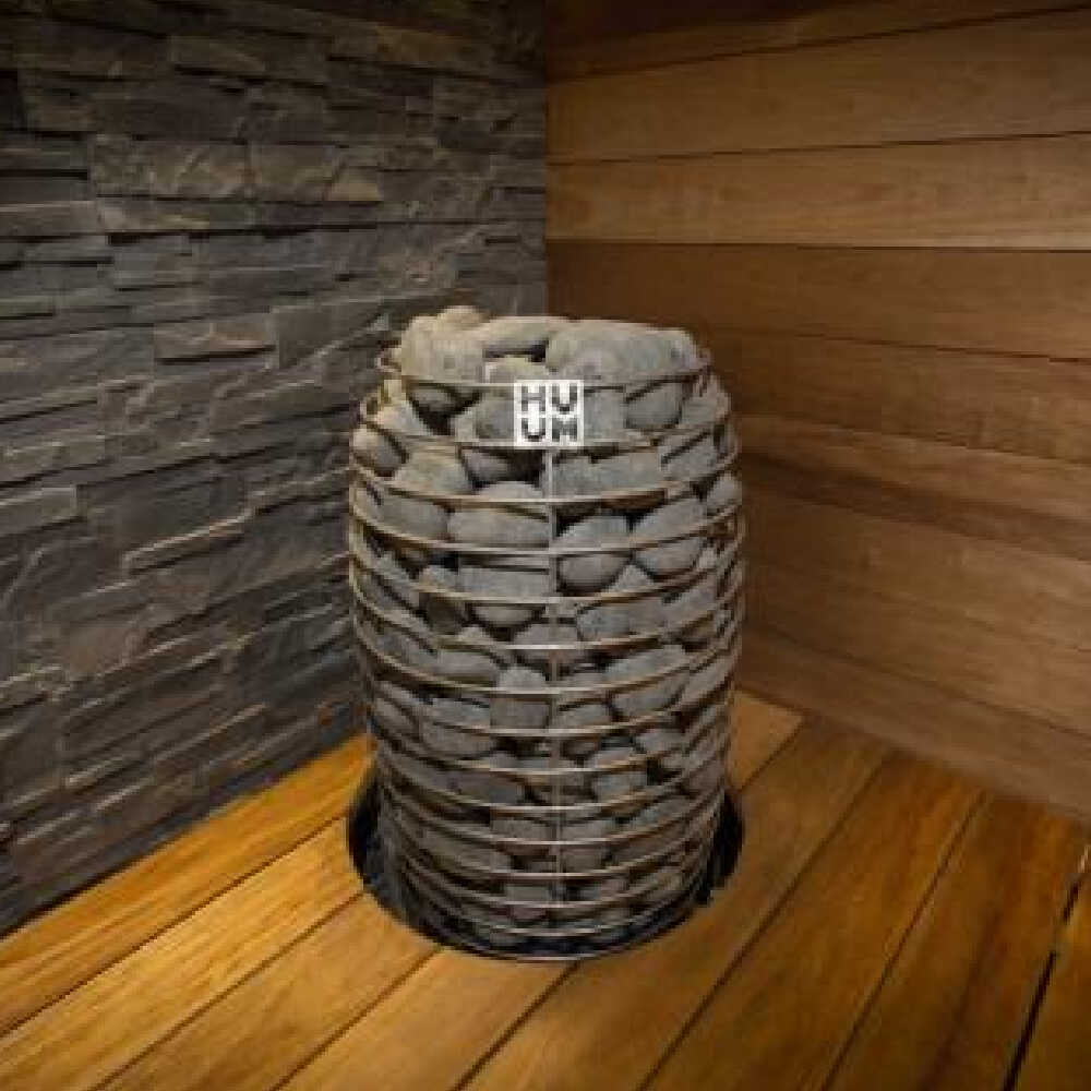 Huum Hive Mini steel sauna heater with digital controller and sauna stones, floor mount, viewed from top angle.