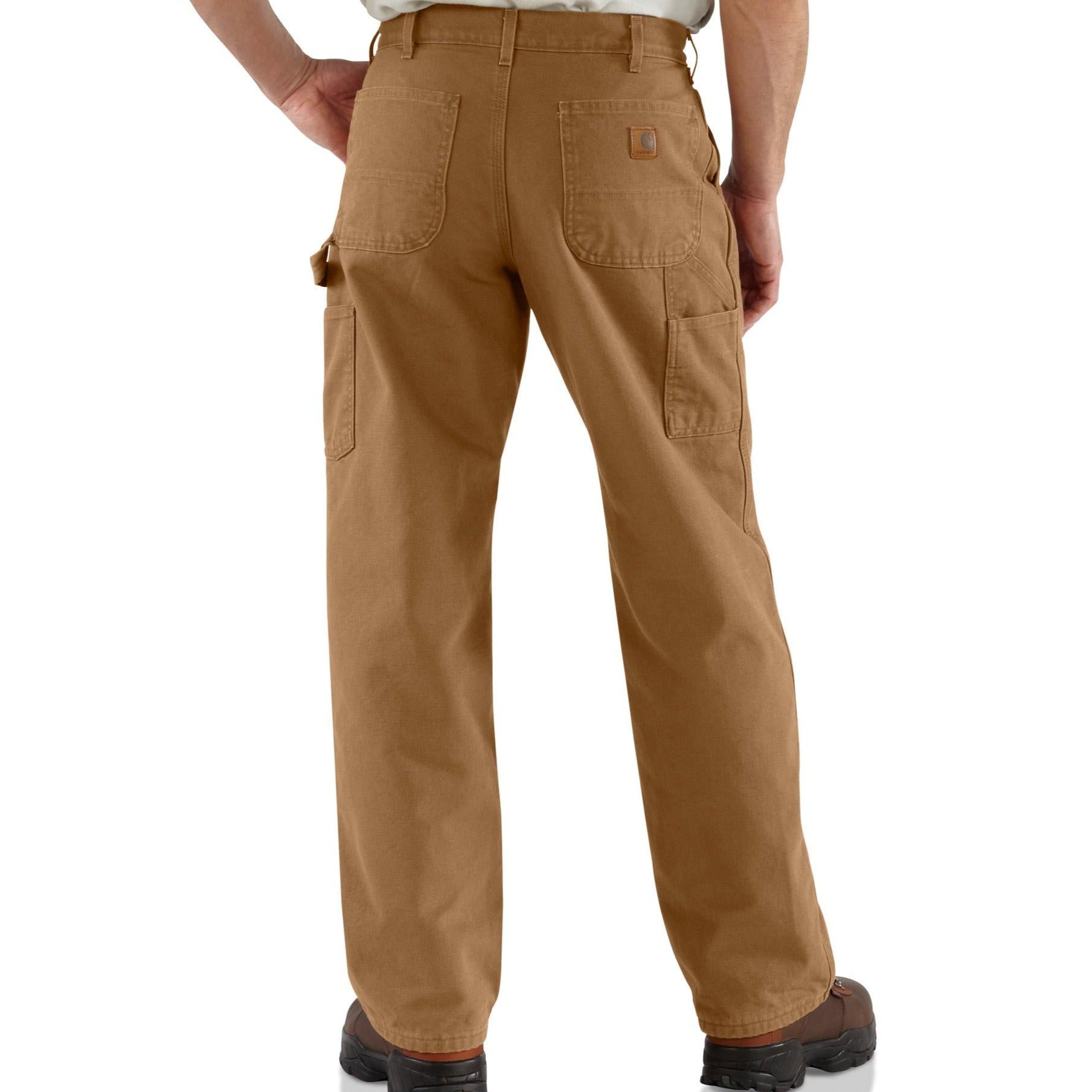 Khaki Carhartt carpenter jeans for men, featuring a relaxed fit and multiple pockets, displayed on a wooden background.