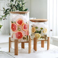 Large glass drink dispenser with stand by Tea + Linen, clear container with spigot for serving beverages.