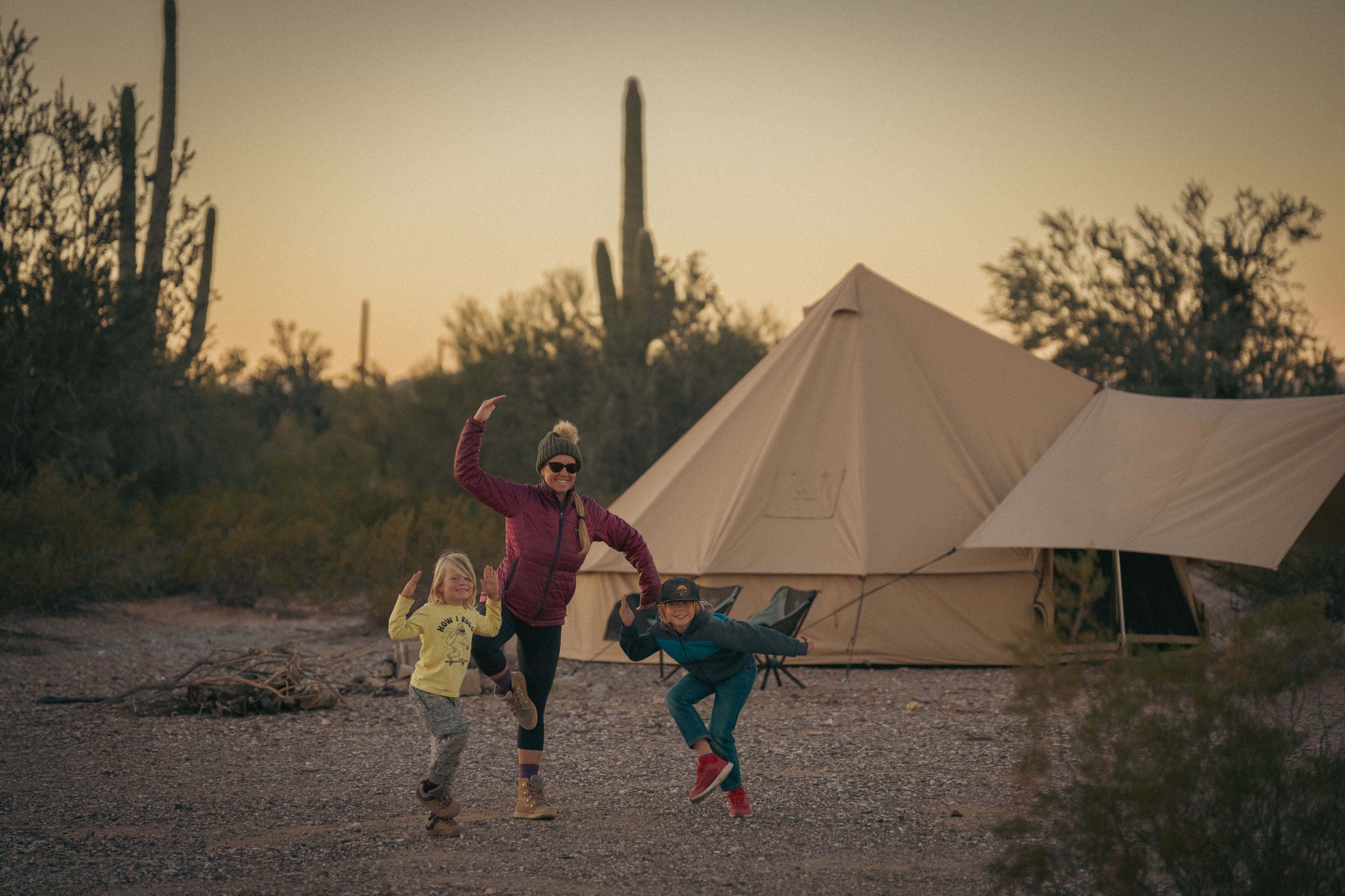 White Duck Outdoors Regatta awning attached to a bell tent with mother and kids playing outside in a grassy outdoor setting.