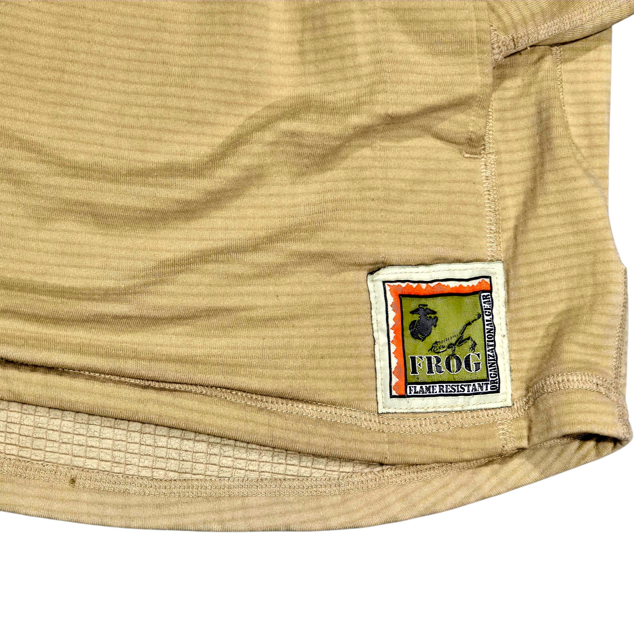 Close-up of a beige ribbed athletic shorts or pants fabric with a sewn-on brand patch reading FROG BACKCROSSING.