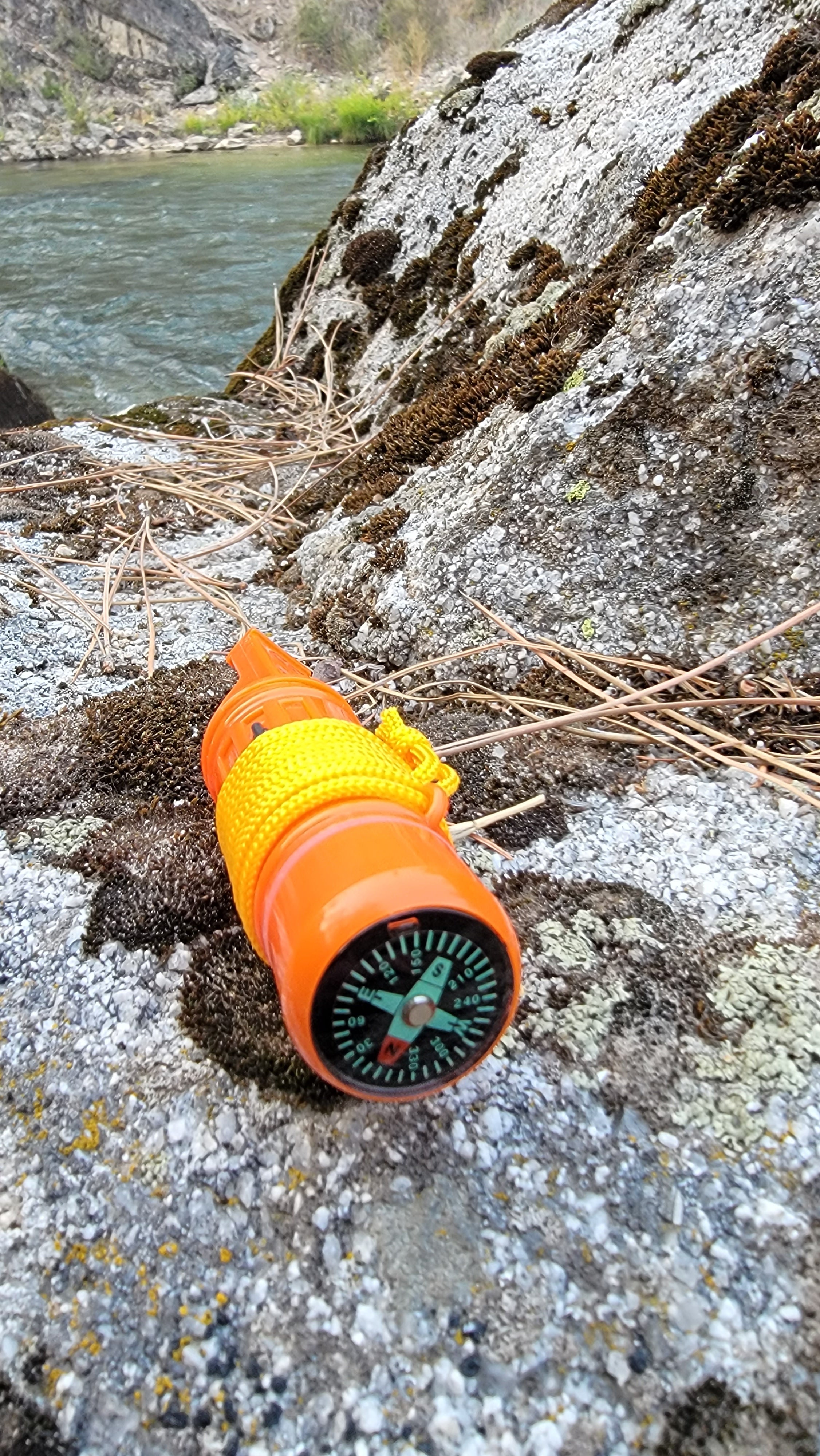 Orange 5-in-1 survival whistle tool for camping and hiking, featuring multiple emergency functions for outdoor safety.