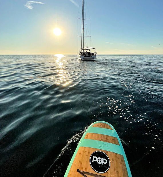Backcountry Sportsman 11'0 Huckleberry sailboat with a sleek hull and colorful design on calm water.