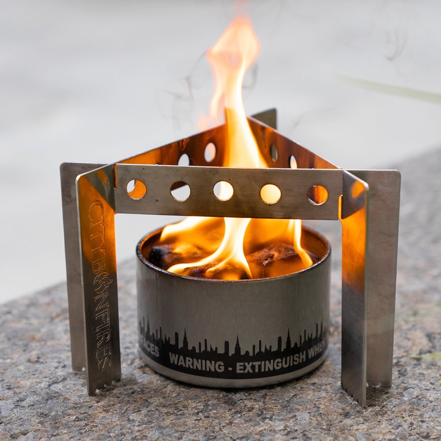 City Bonfires portable camp stove with stand setup in an outdoor setting, ready for cooking over an open flame.