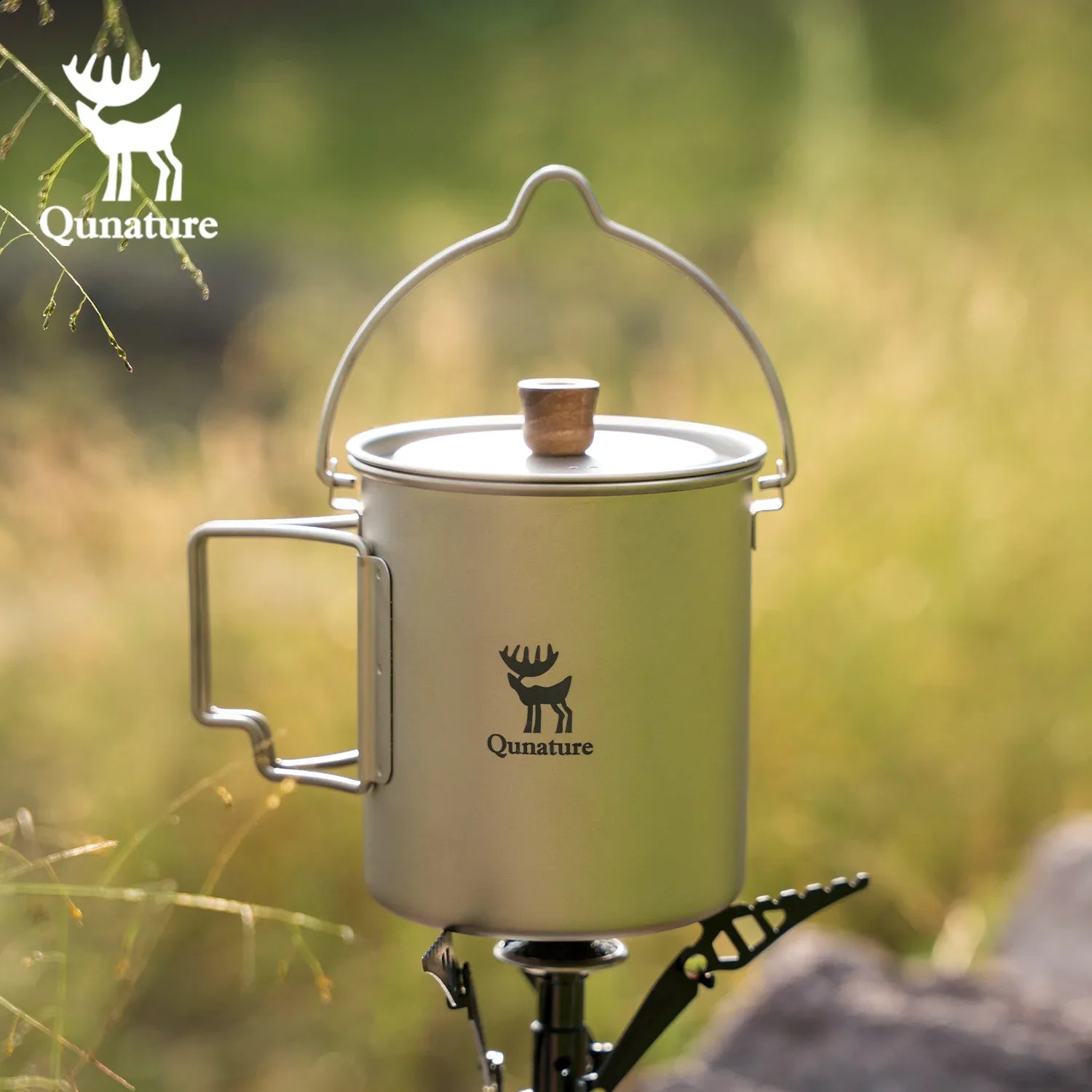 Qunature Global ultralight titanium camping mug 750 ml with a sleek design and sturdy handle in a natural outdoor setting.