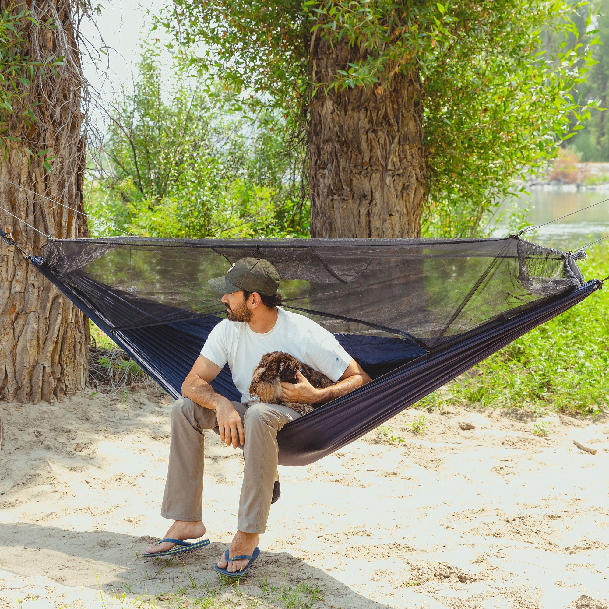 GrandTrunk Skeeter Beeter XT mosquito net hammock set up in a wooded area, showcasing its protective netting and comfortable design.