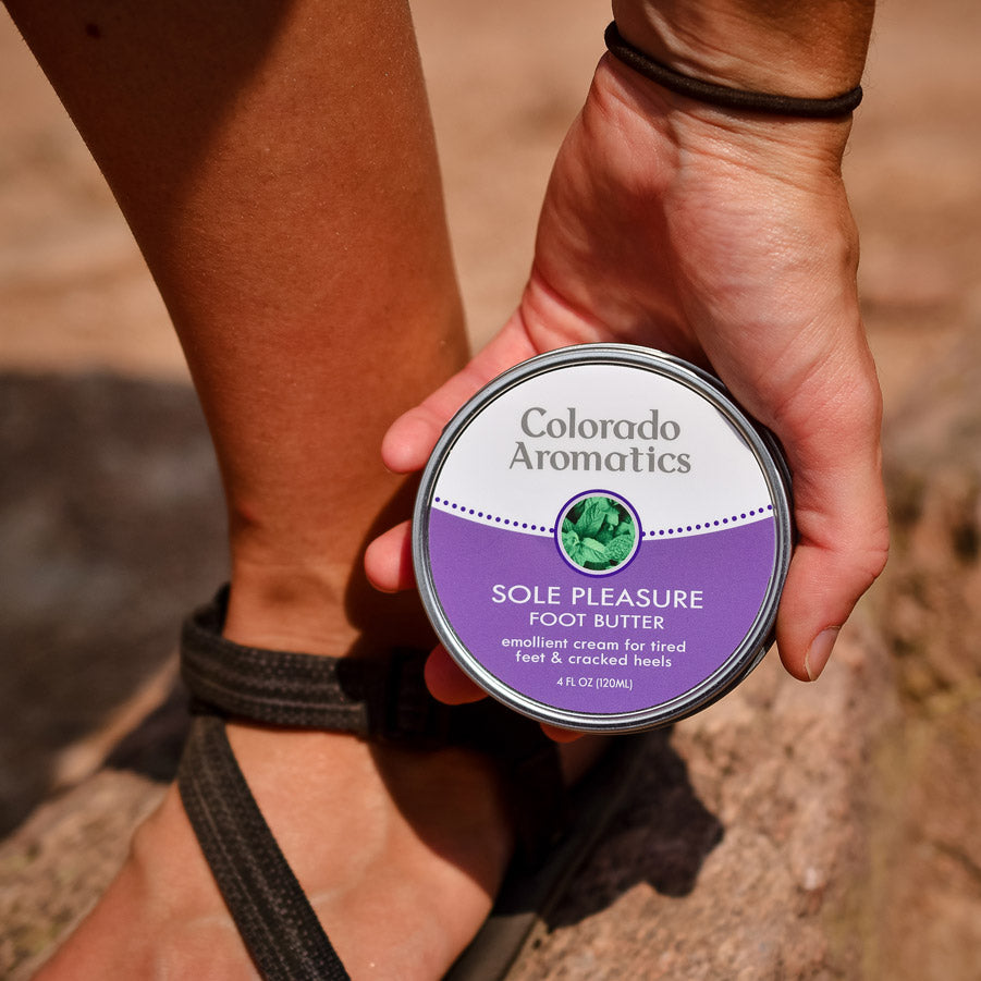 Colorado Aromatics Sole Pleasure Foot Butter Balm applied on a trail, showcasing nourishing foot care for tired, dry feet.