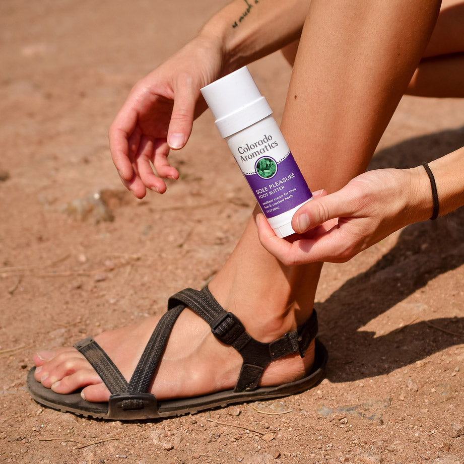 Tube of Colorado Aromatics Sole Pleasure Foot Butter Balm on a trail, showcasing natural foot care product for healthy, moisturized feet.