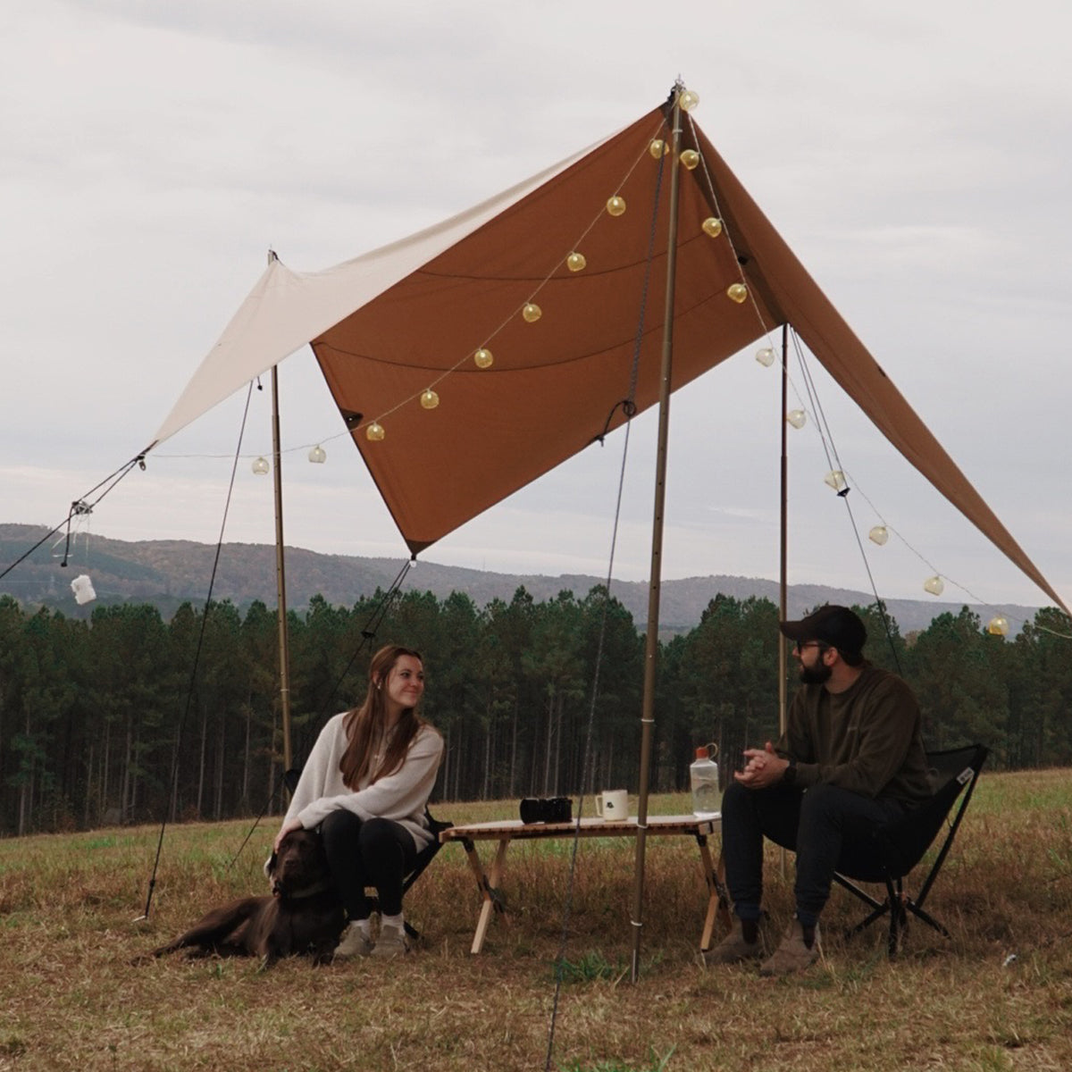 White Duck Outdoors Sunshade Tarp 400 set up outdoors with a couple enjoying the shaded area. Durable outdoor sunshade tarp.