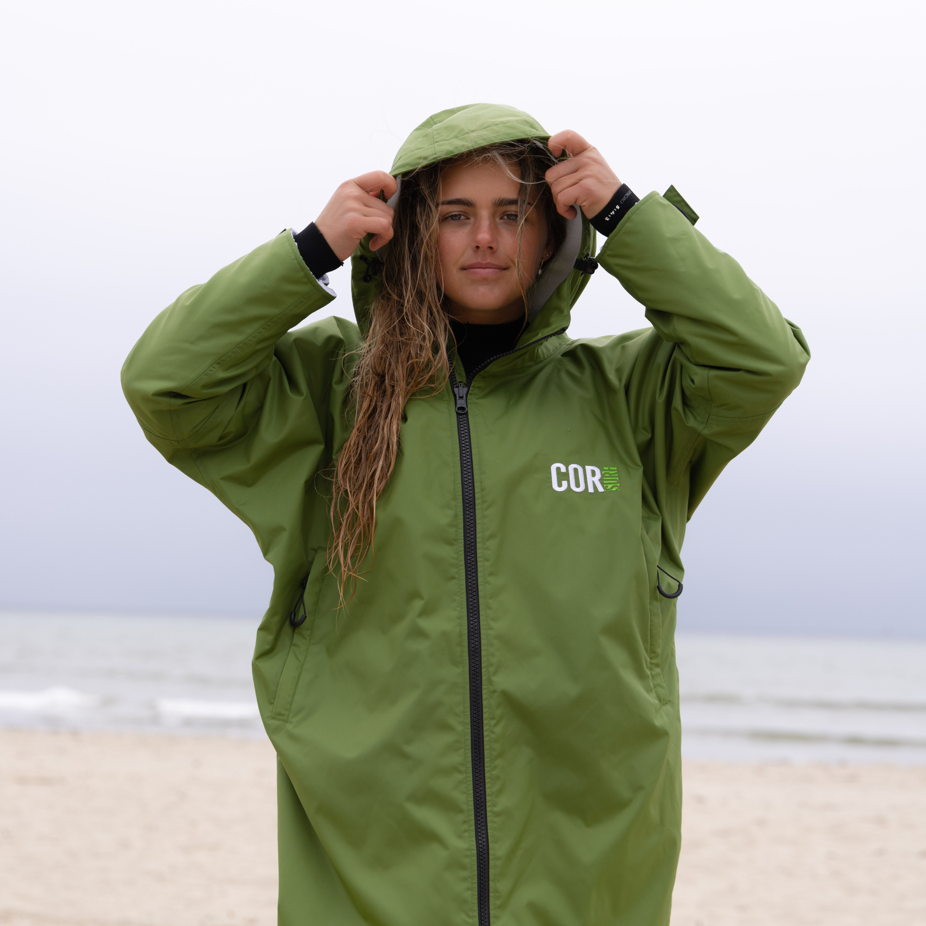 COR Surf waterproof swim parka for women, youth, and kids featuring a green color and hooded design, ideal for beach and outdoor activities.