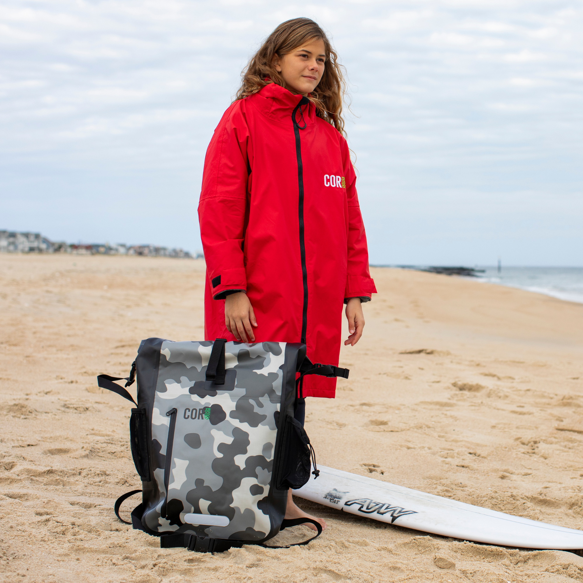 Red COR Surf waterproof swim parka for kids, shown as a towel-style jacket with hood, suitable for boys and girls.