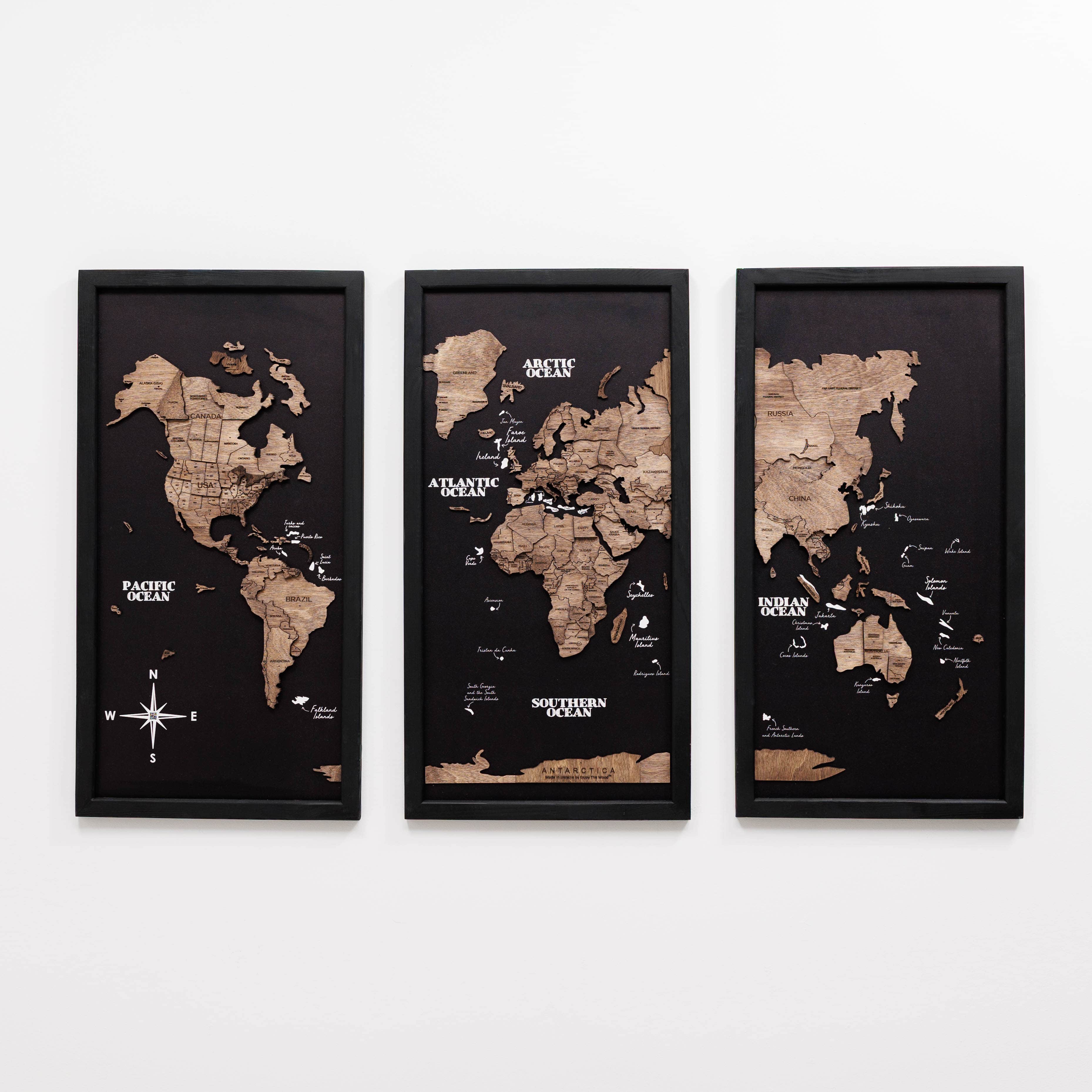 Dark walnut wooden triptych world map by Enjoy The Wood, showing three panels with detailed carved continents and ocean lines.