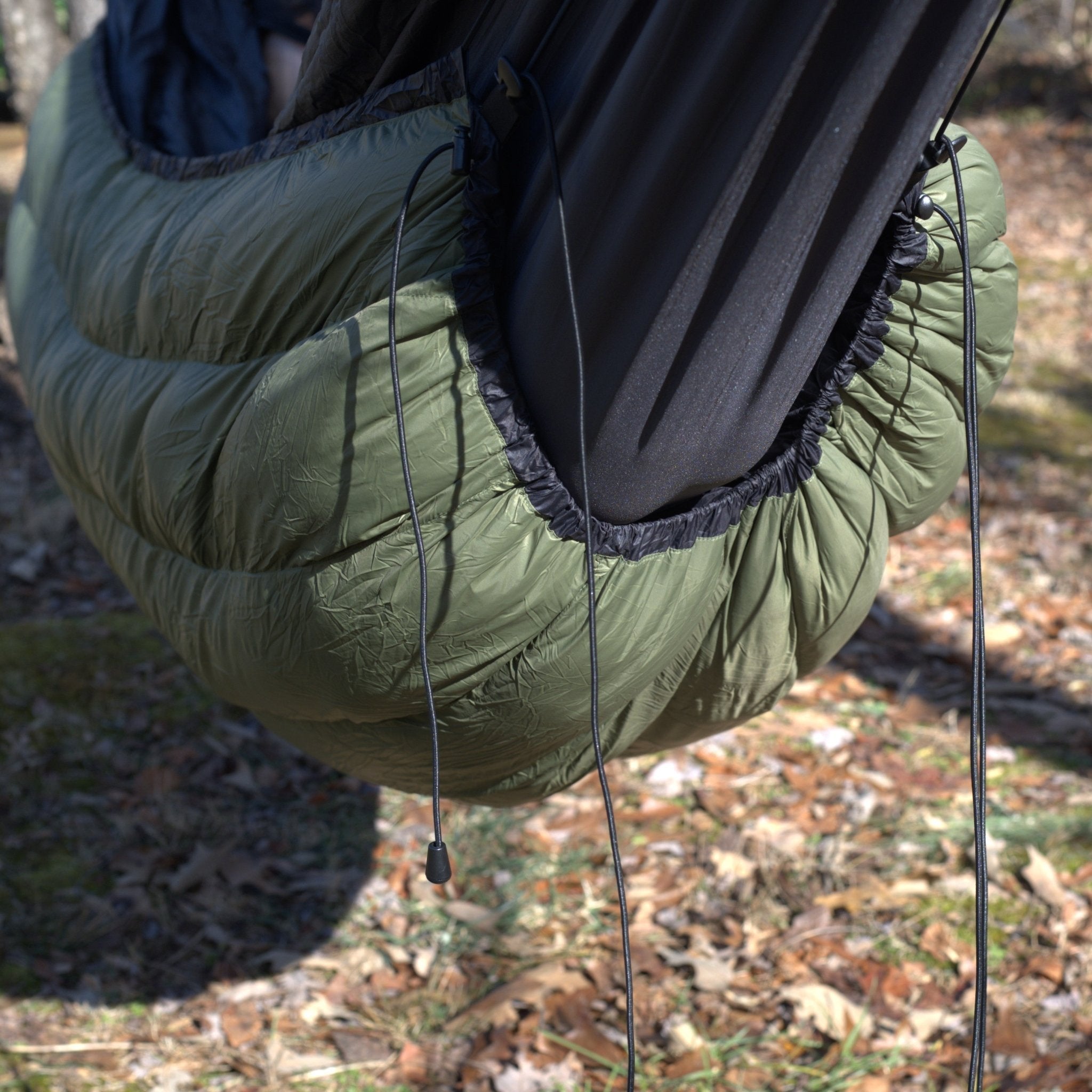 Hanging High Hammocks EmberNest Underquilt 30°F rated in a cozy campsite setting, designed for outdoor hammock camping warmth.