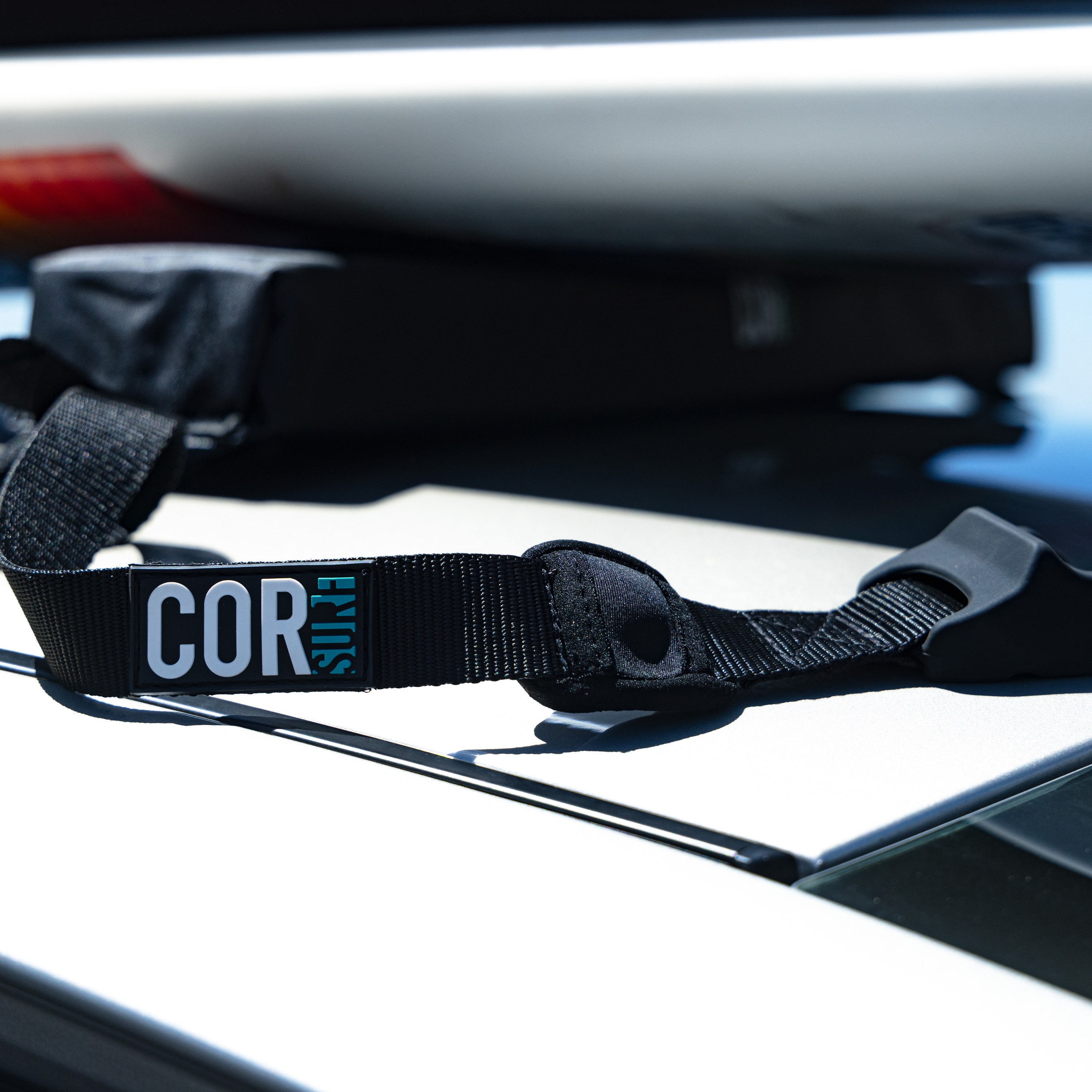 COR Surf universal soft car racks for surfboards, SUPs, canoes, and kayaks, securely fastened to vehicle roof for transport.