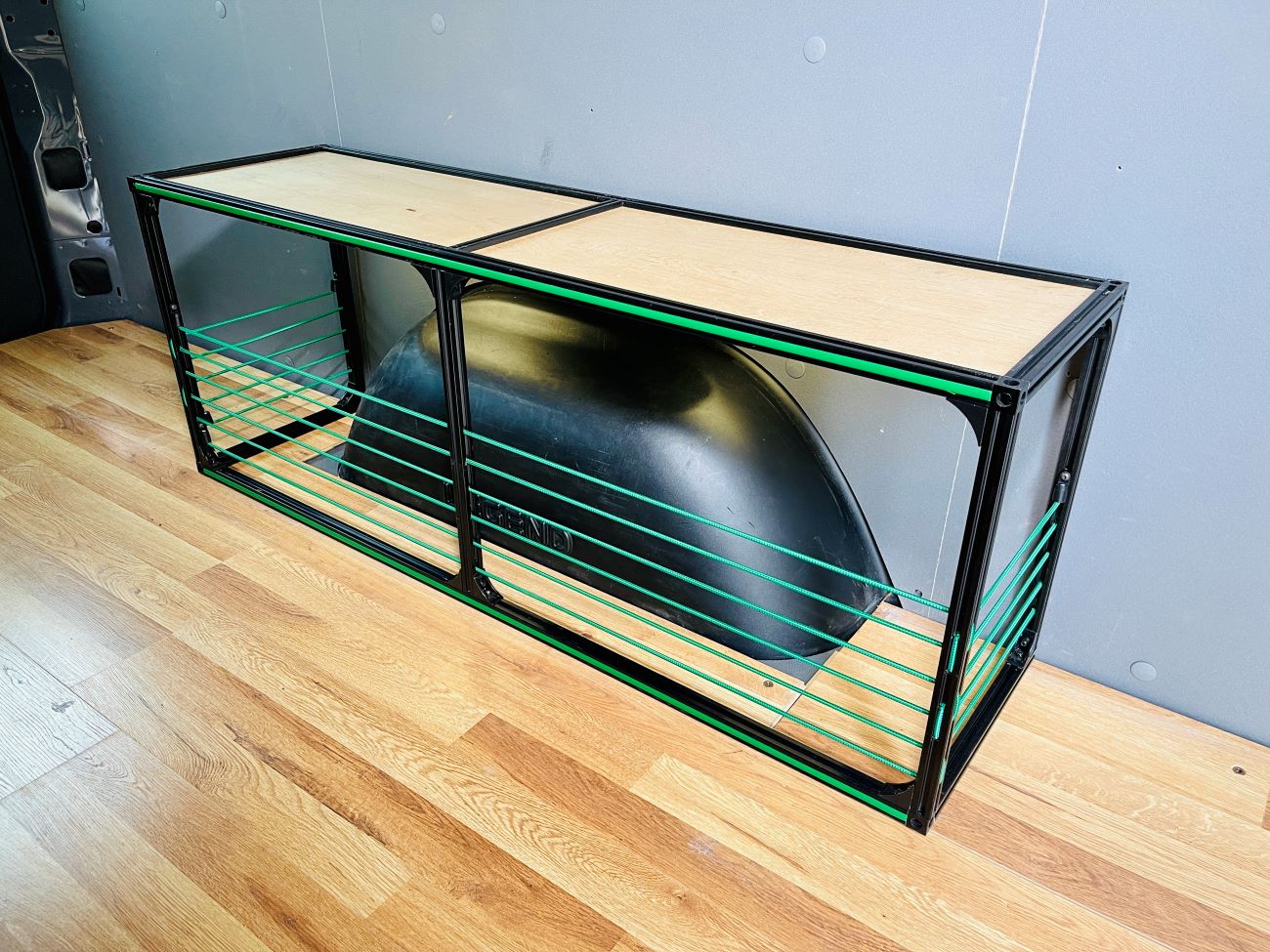 Van wheel well bench storage inside a camper van conversion by TNTvans, showing built-in wooden bench with storage compartments.