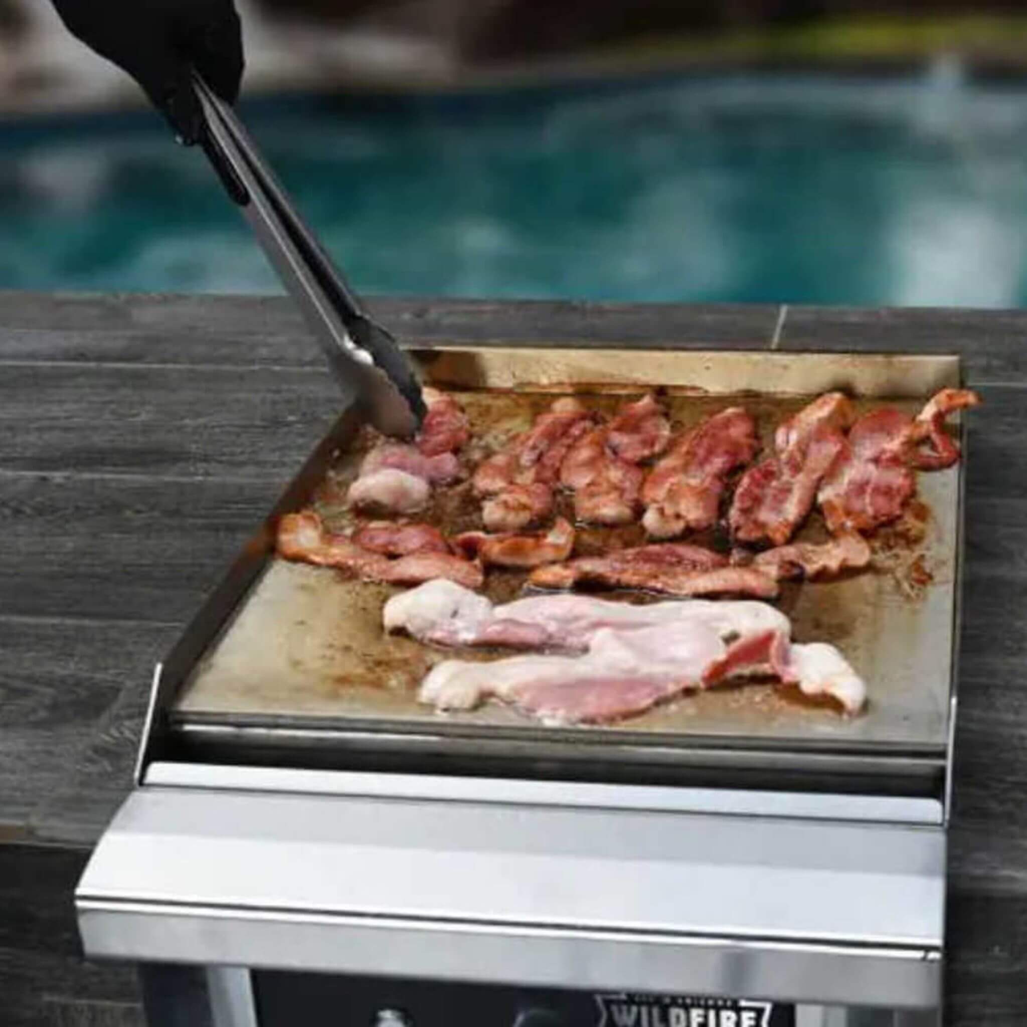 15-inch Ranch Pro stainless steel side griddle by Wildfire Outdoor Living, showcasing outdoor grilling in action.