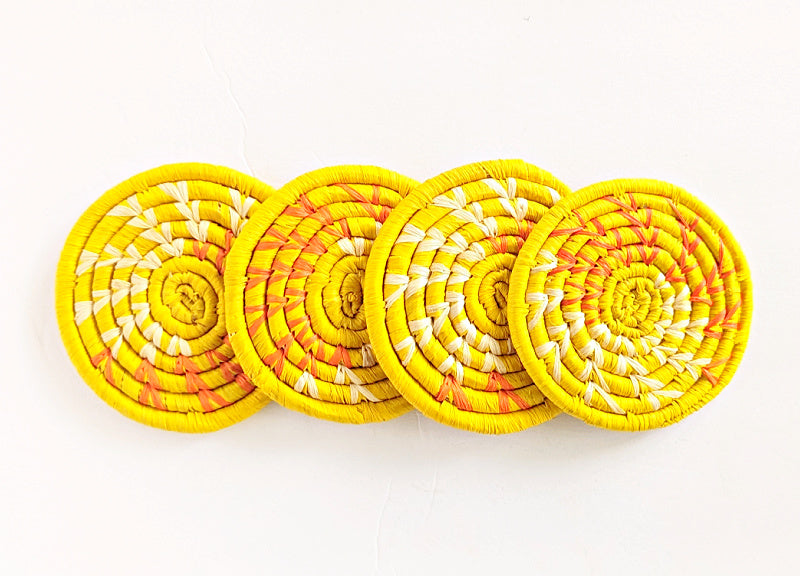 Set of four handmade woven drink coasters in vibrant yellow and natural raffia, designed by Reflektion Design.